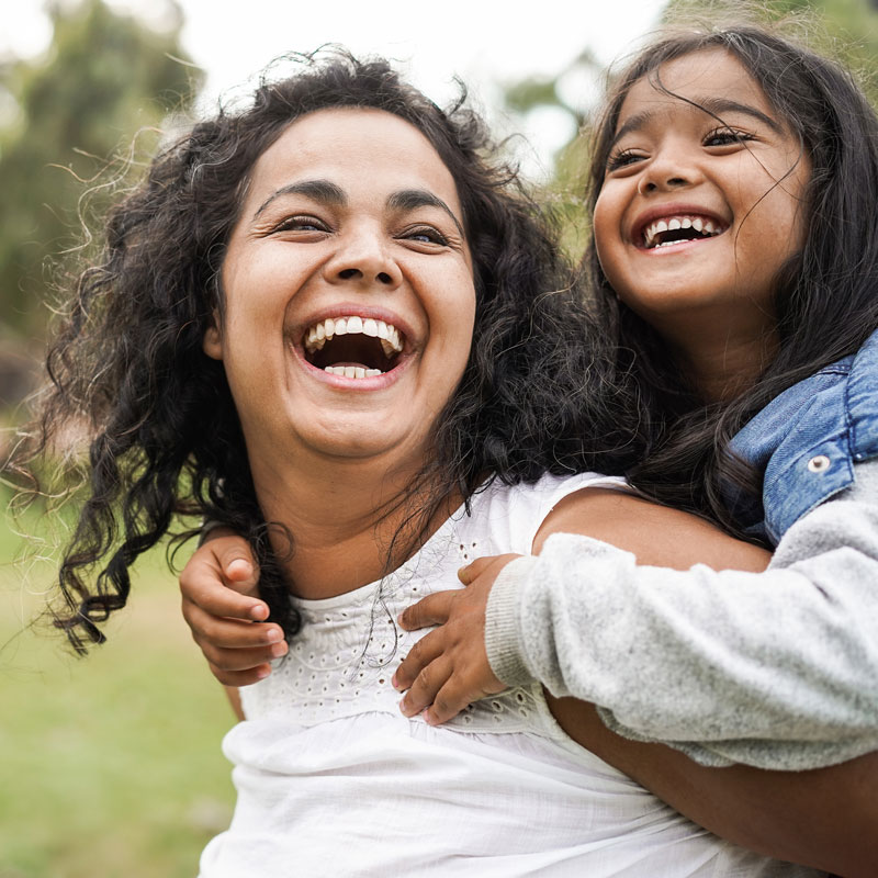 mom and young daughter laughing outdoors